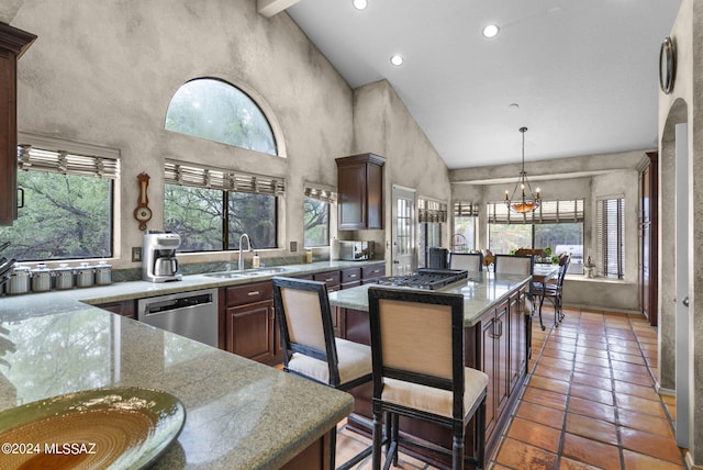 kitchen with an inviting chandelier, a sink, high vaulted ceiling, a center island, and stainless steel appliances