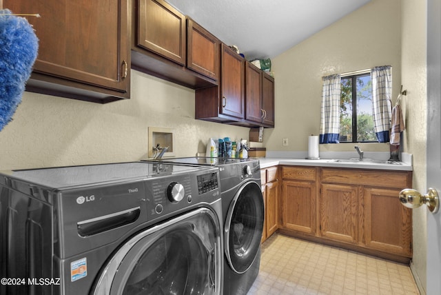 laundry area with a textured wall, washing machine and dryer, light floors, a sink, and cabinet space