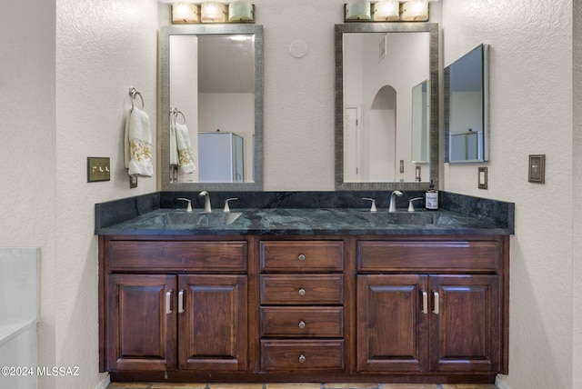 bathroom featuring double vanity, a sink, and a textured wall
