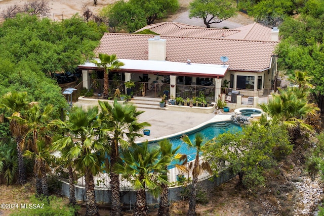back of property featuring a patio, an in ground hot tub, fence, and a tile roof