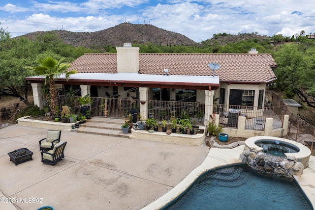 rear view of house with a patio area, a tile roof, and a chimney