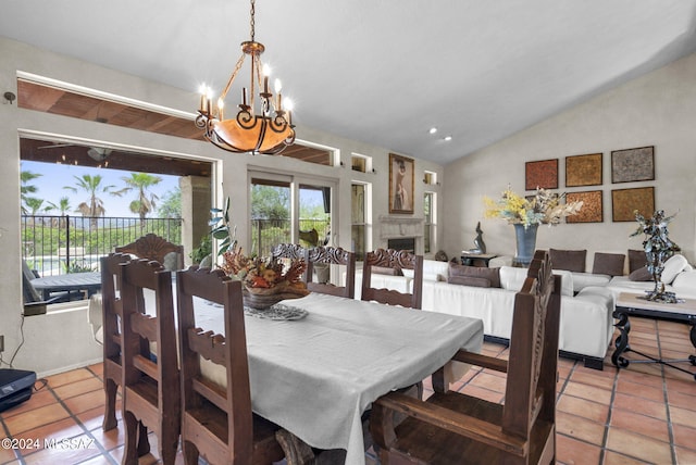 dining area with a fireplace, vaulted ceiling, a chandelier, and a wealth of natural light