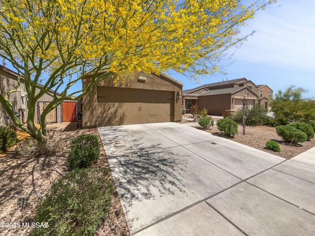view of front of property with a garage, a gate, stucco siding, and concrete driveway