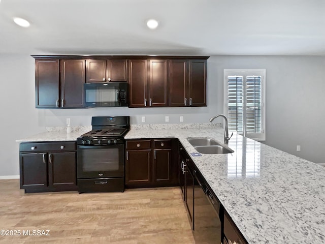 kitchen featuring a sink, light stone countertops, black appliances, and dark brown cabinets