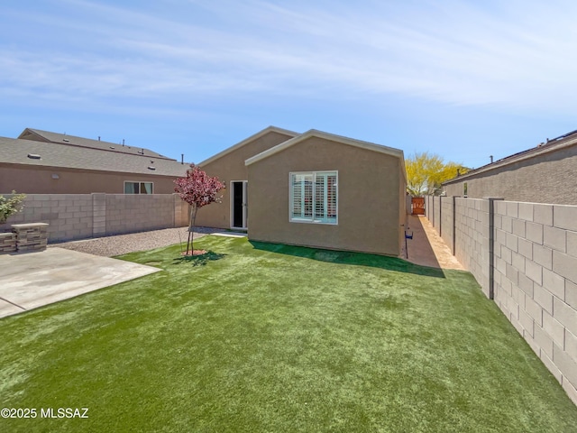 rear view of property with a fenced backyard, stucco siding, and a yard