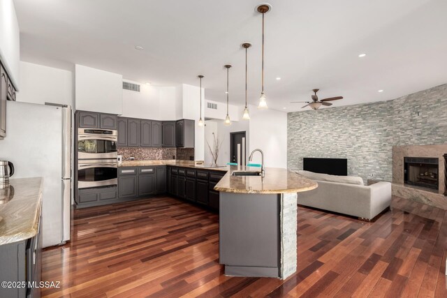 1330 W Panorama Rd, Tucson, AZ 85704 - kitchen featuring freestanding refrigerator, a peninsula, a stone fireplace, gray cabinets, and a sink