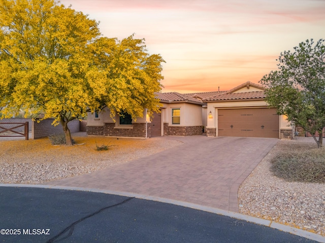 view of front facade with an attached garage, stone siding, stucco siding, decorative driveway, and a tiled roof