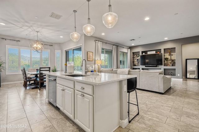 kitchen with recessed lighting, an inviting chandelier, an island with sink, and a sink