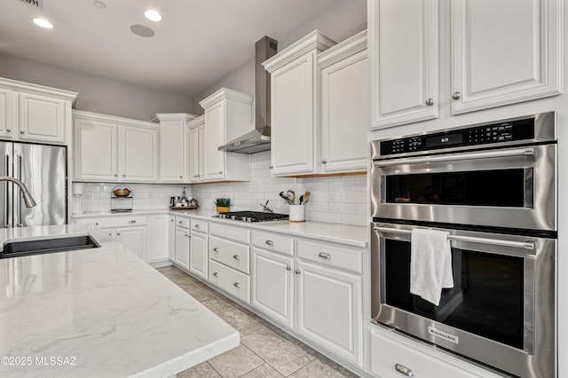 kitchen featuring wall chimney range hood, stainless steel appliances, and white cabinetry