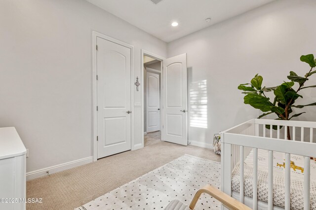 bedroom with baseboards, recessed lighting, a nursery area, and light carpet