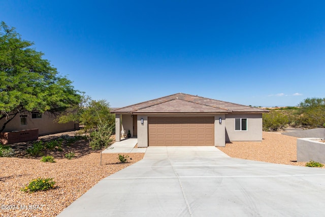 view of front of property with concrete driveway, a garage, a tile roof, and stucco siding