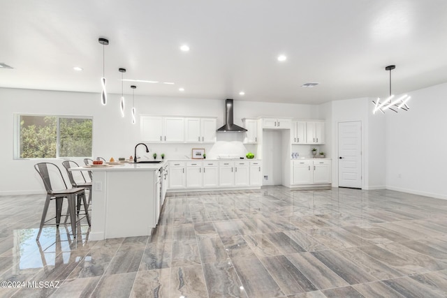 kitchen with baseboards, a sink, recessed lighting, and wall chimney range hood