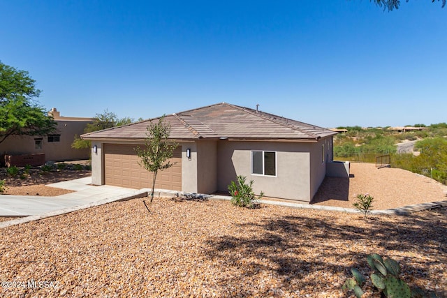 ranch-style home with a garage, stucco siding, and concrete driveway