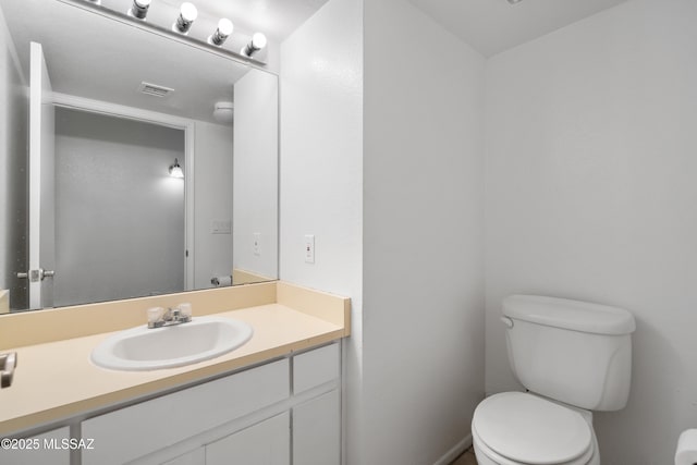 half bathroom featuring vanity, toilet, and visible vents