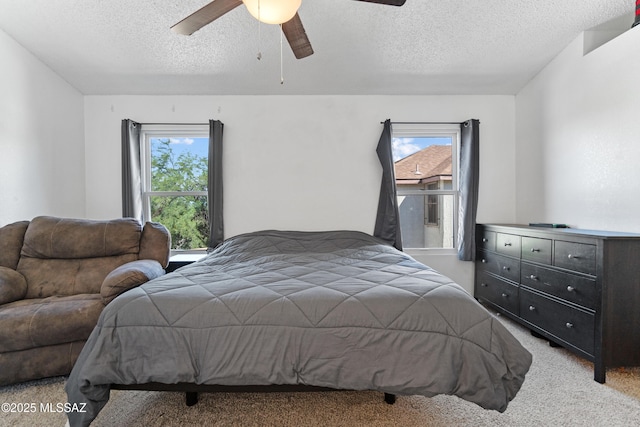 bedroom with light colored carpet, a textured ceiling, and multiple windows