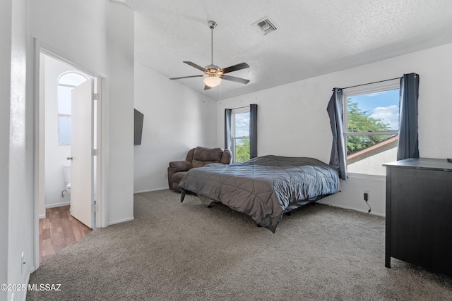 bedroom with carpet flooring, a textured ceiling, visible vents, and multiple windows