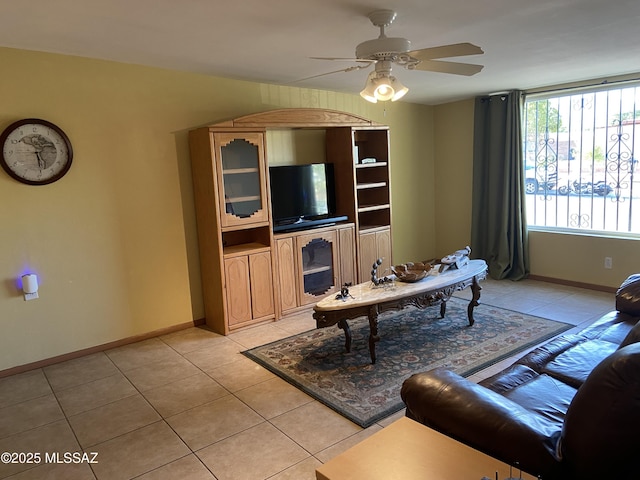 living area featuring baseboards, a ceiling fan, and light tile patterned floors