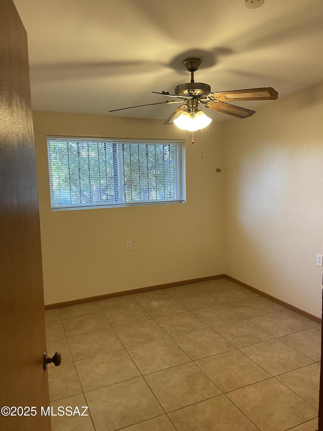empty room featuring baseboards, a ceiling fan, and light tile patterned flooring