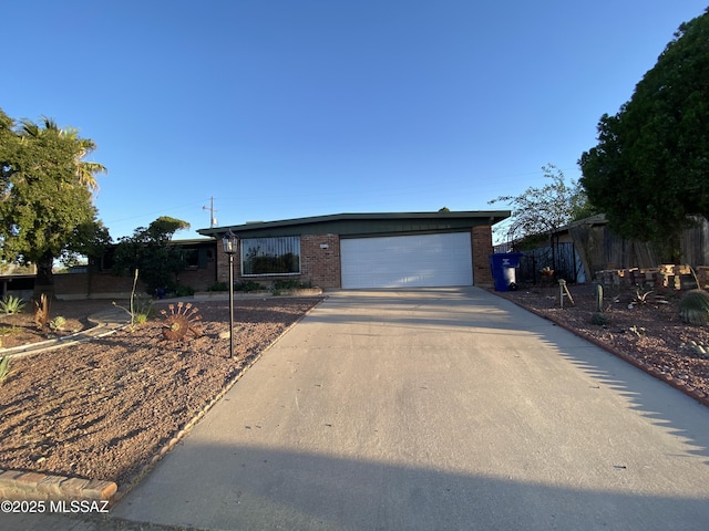 ranch-style house with brick siding, an attached garage, and concrete driveway