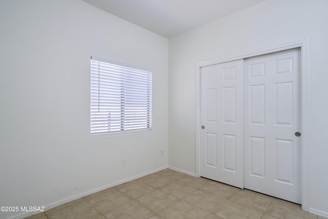 unfurnished bedroom with a closet, baseboards, and light tile patterned floors