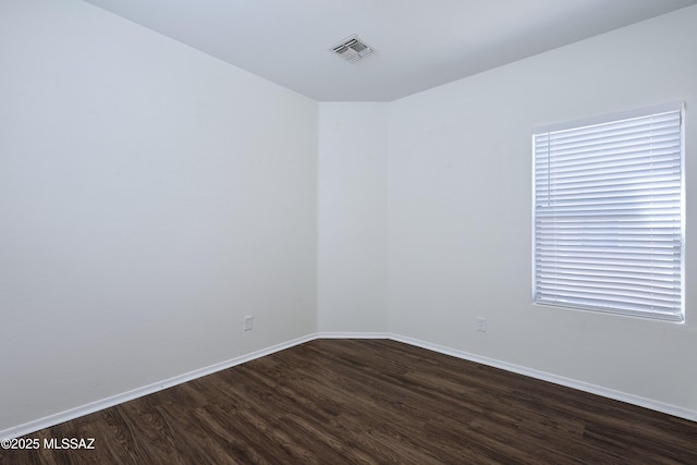 unfurnished room with baseboards, dark wood finished floors, and visible vents
