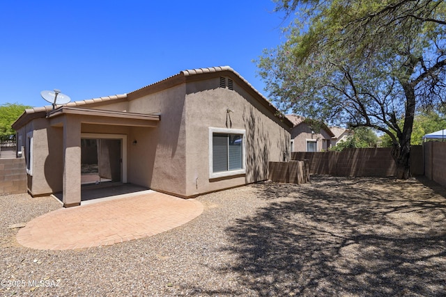 back of property featuring a patio, fence, a tile roof, and stucco siding