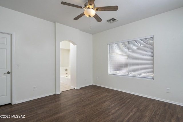 unfurnished bedroom featuring arched walkways, baseboards, visible vents, and wood finished floors