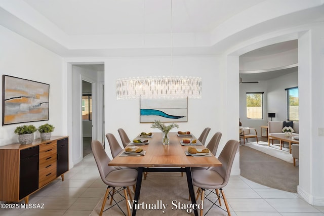 dining space featuring baseboards, a tray ceiling, and light tile patterned flooring