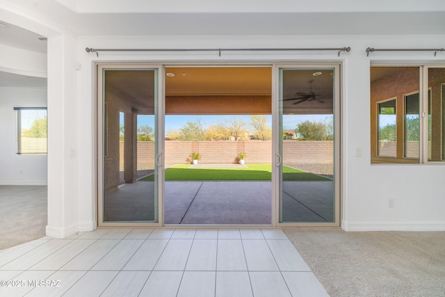 doorway to outside featuring baseboards, carpet flooring, and tile patterned floors