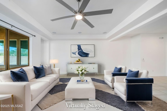 living room with a ceiling fan, tile patterned floors, baseboards, and a raised ceiling