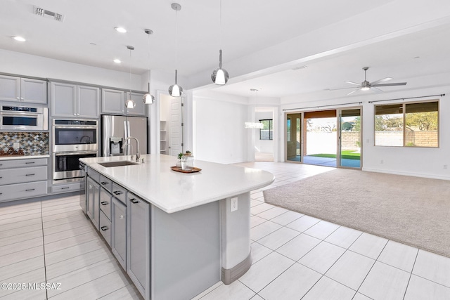 kitchen with a sink, gray cabinets, open floor plan, and stainless steel appliances