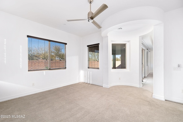empty room with a ceiling fan, baseboards, and light carpet