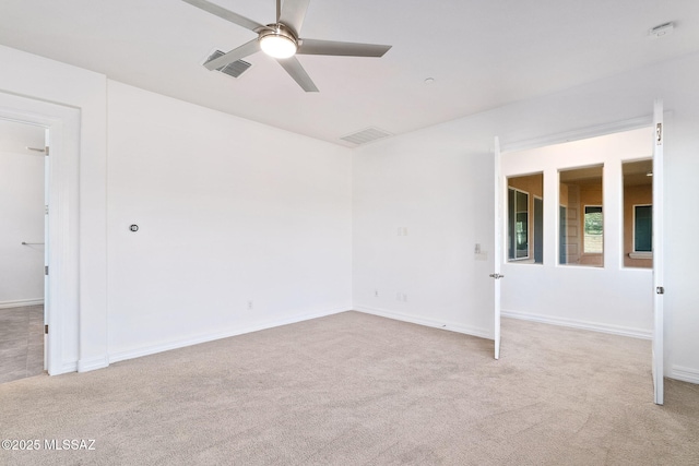 spare room featuring baseboards, ceiling fan, light carpet, and visible vents