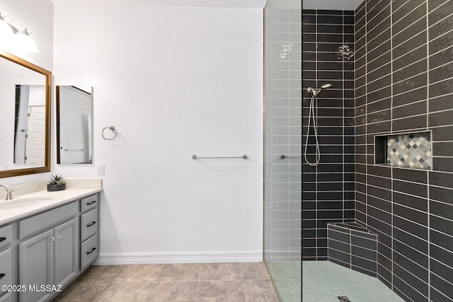 full bath featuring vanity, baseboards, and walk in shower
