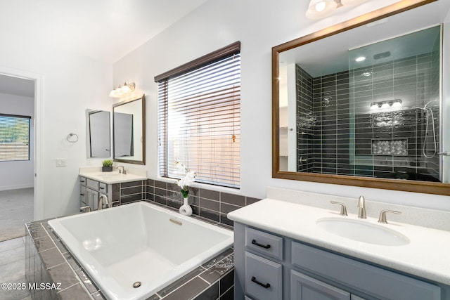full bath with baseboards, two vanities, a sink, and a bath