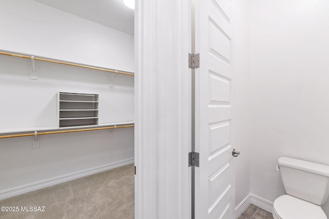 bathroom featuring baseboards, toilet, and a walk in closet