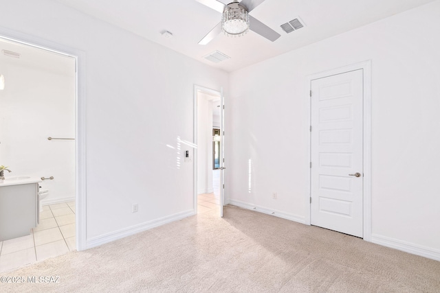 unfurnished bedroom featuring connected bathroom, visible vents, light carpet, and a sink