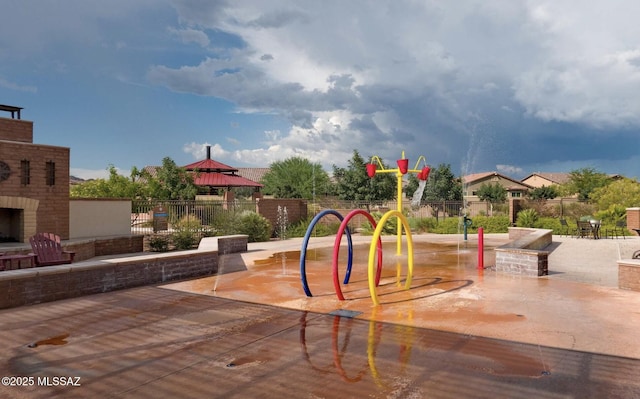 community play area with a gazebo, fence, a patio area, and an outdoor brick fireplace