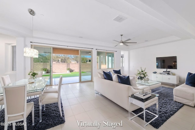 living area with light tile patterned floors, ceiling fan with notable chandelier, a tray ceiling, and visible vents