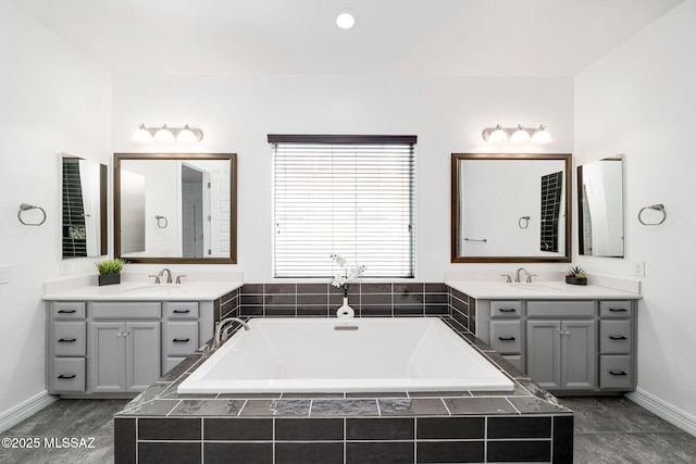bathroom with two vanities, a sink, and a bath