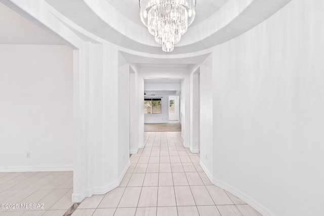 hallway with baseboards, light tile patterned flooring, and a notable chandelier