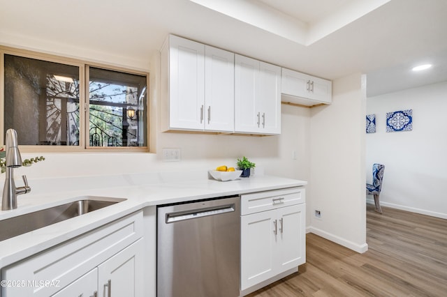 kitchen featuring dishwasher, a sink, light countertops, light wood-style floors, and white cabinetry