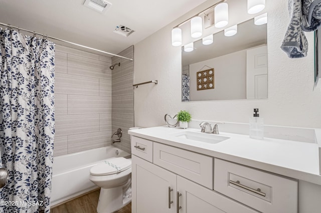 bathroom featuring visible vents, vanity, wood finished floors, toilet, and shower / tub combo