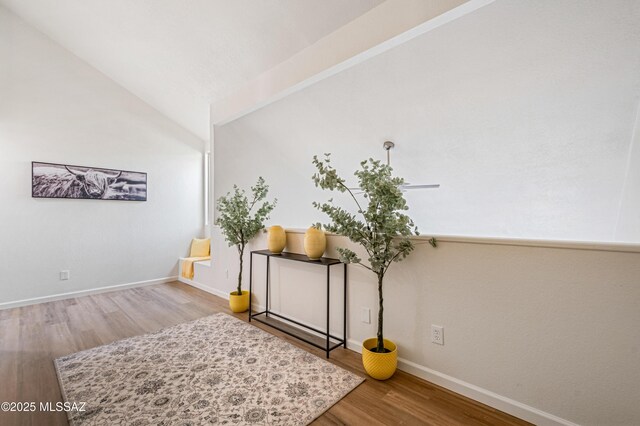 interior space featuring baseboards, wood finished floors, and lofted ceiling