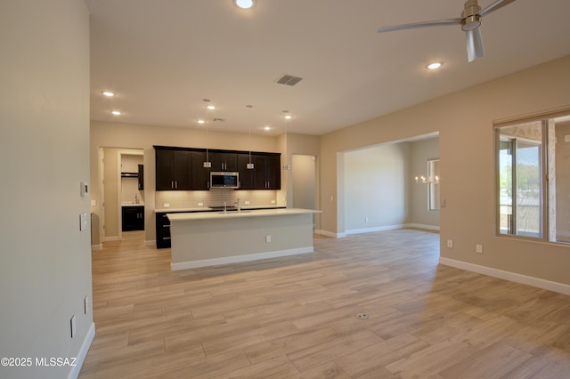 62908 E Thunder Rock Dr, Tucson, AZ 85739 - kitchen with a sink, stainless steel microwave, ceiling fan with notable chandelier, open floor plan, and light countertops