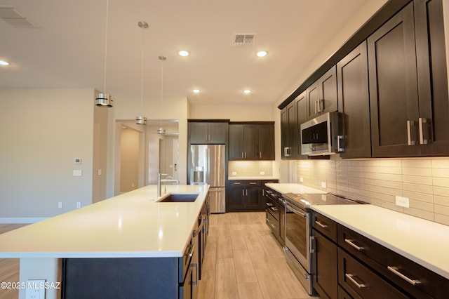 62908 E Thunder Rock Dr, Tucson, AZ 85739 - kitchen with a sink, stainless steel appliances, light wood-type flooring, visible vents, and light countertops