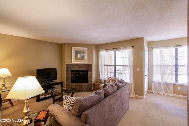 living area featuring a tiled fireplace, baseboards, and light colored carpet