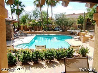 community pool with a fenced backyard and a patio area