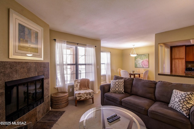 living room featuring baseboards, a tiled fireplace, and carpet