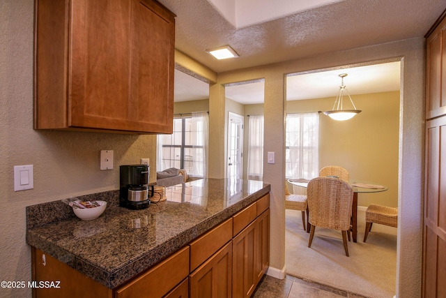 kitchen with baseboards, carpet, tile countertops, and brown cabinets